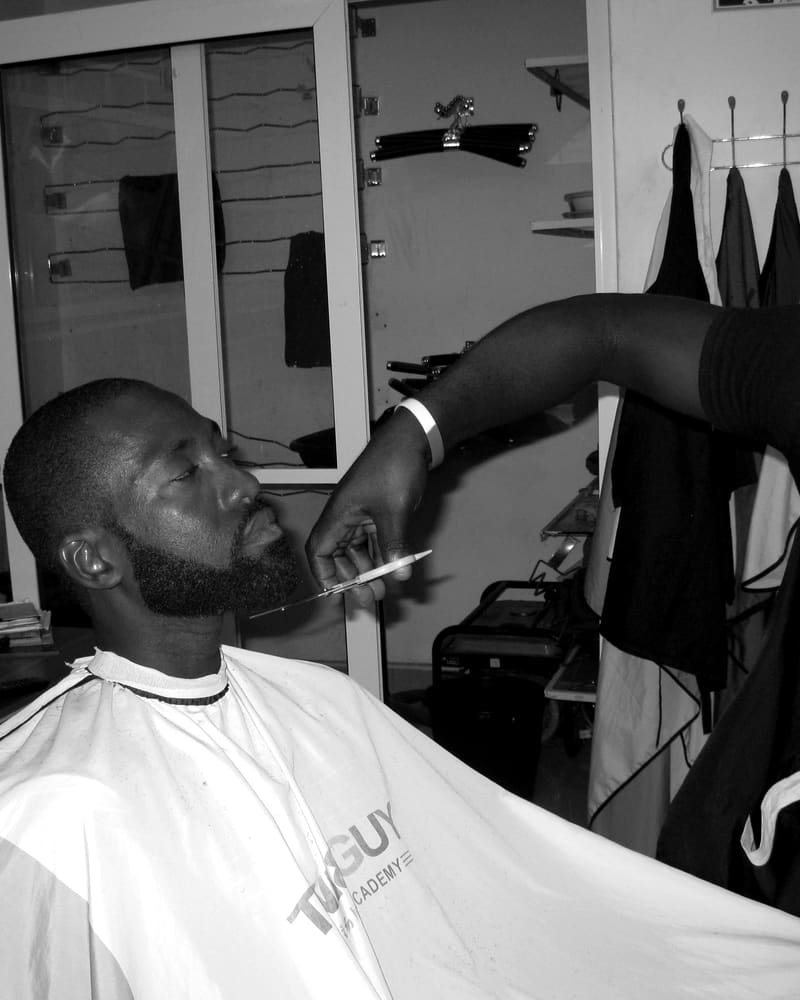 Barbero perfilando la barba de un cliente