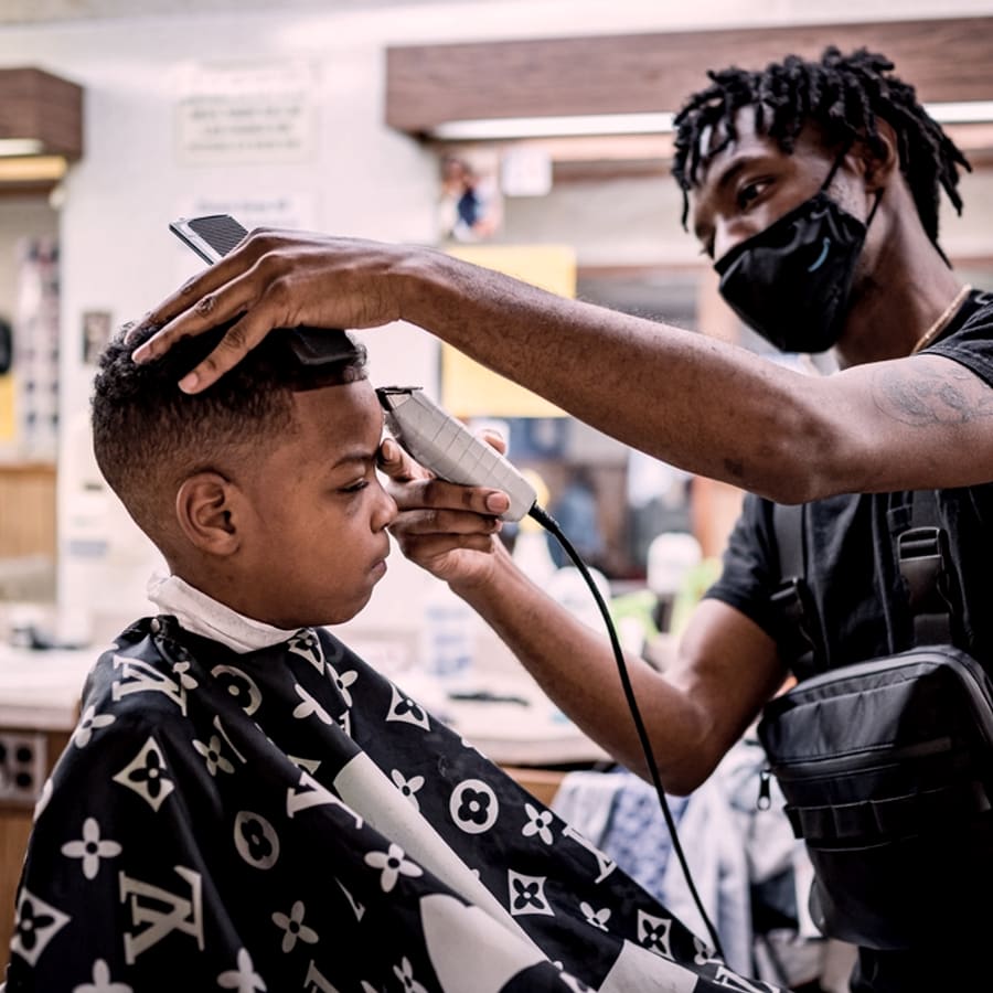 Barbero recortando el cabello de un cliente joven
