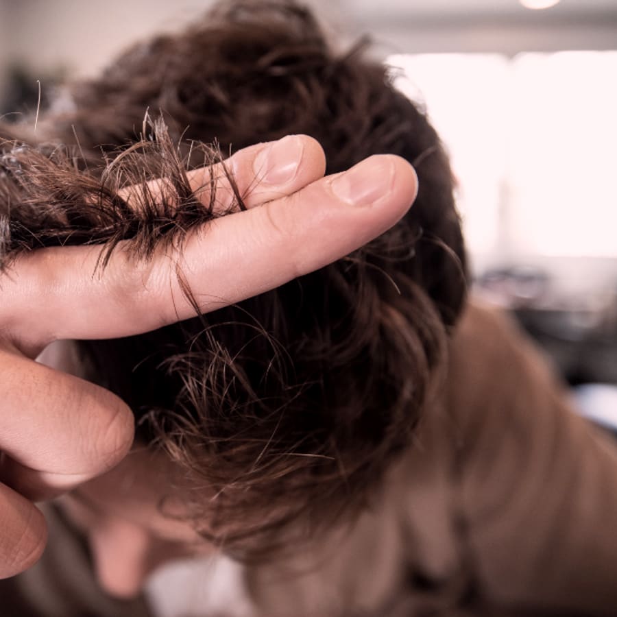 Mano sosteniendo un mechón de cabello antes de cortarlo