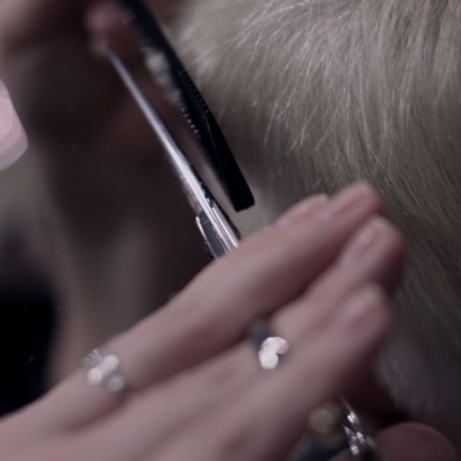 Tijera cortando cabello cano a contraluz