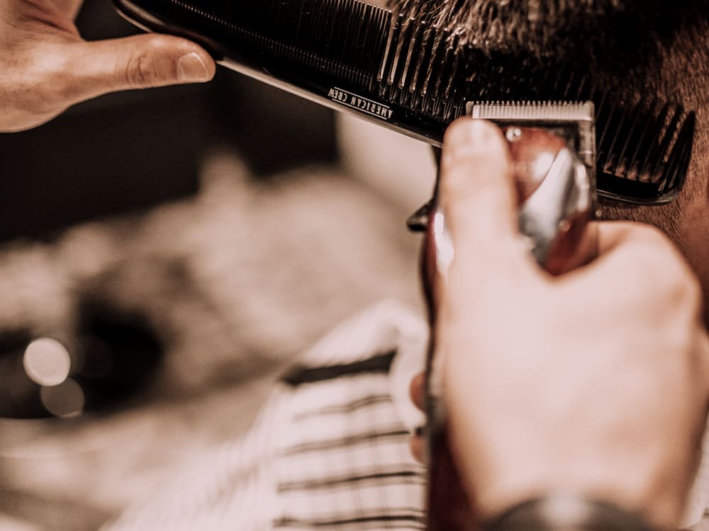 Barbero recortando el cabello con máquina sobre peine